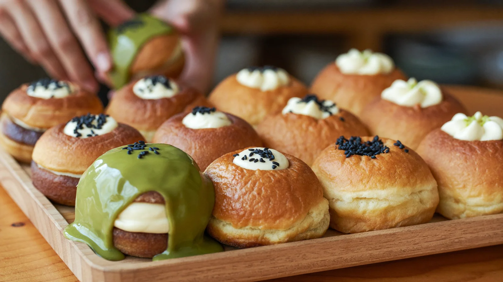 A close-up of glossy cream-filled Korean doughnuts and cream buns arranged on a bakery display counter, soft natural lighting, a local Hong Kong Chinese customer blurred in the background, illustrative image for this Abebe Bakery Tsim Sha Tsui opening guide, not a photo of the actual venue or products