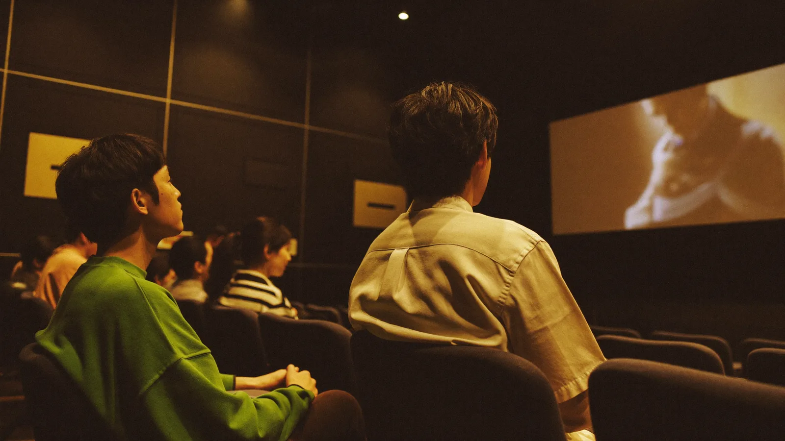 A dimly lit cinema auditorium with a glowing screen and rows of empty seats - illustrative hero for this Hong Kong film festival guide, not a photo of M+ Cinema itself