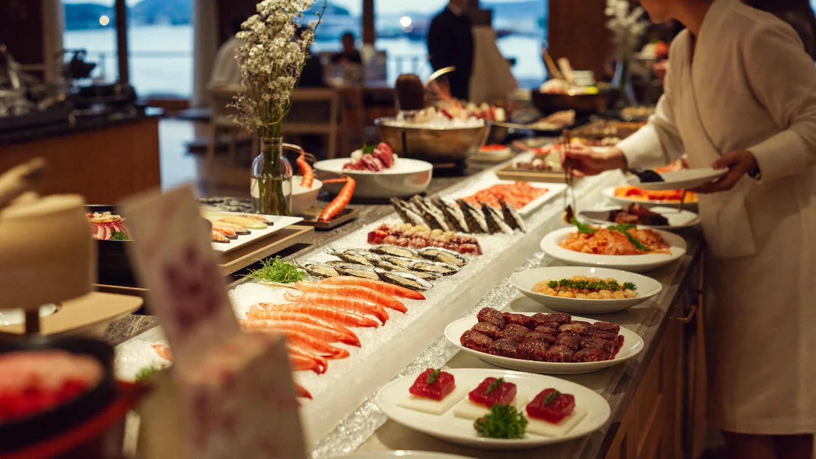 酒店自助餐檯上鋪滿新鮮海鮮、壽司同燒味，有食客正在自助取餐 —— 此為香港自助餐指南嘅示意圖片，並非某間指名食肆嘅實照