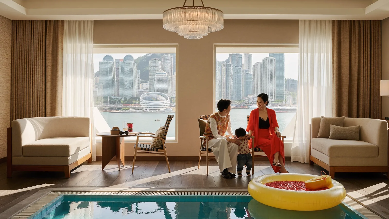 A family relaxing by a hotel pool with a Hong Kong harbour view, illustrating a guide to the best family hotels in Hong Kong