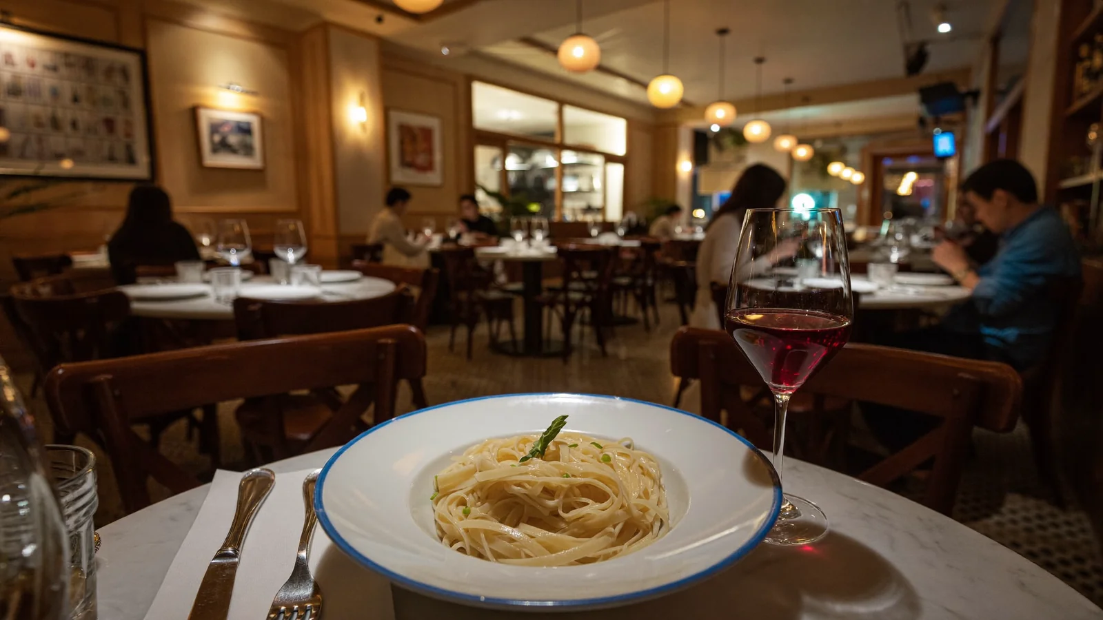A plate of fresh pasta and a glass of red wine in a warm Italian restaurant, illustrating a guide to the best Italian restaurants in Hong Kong