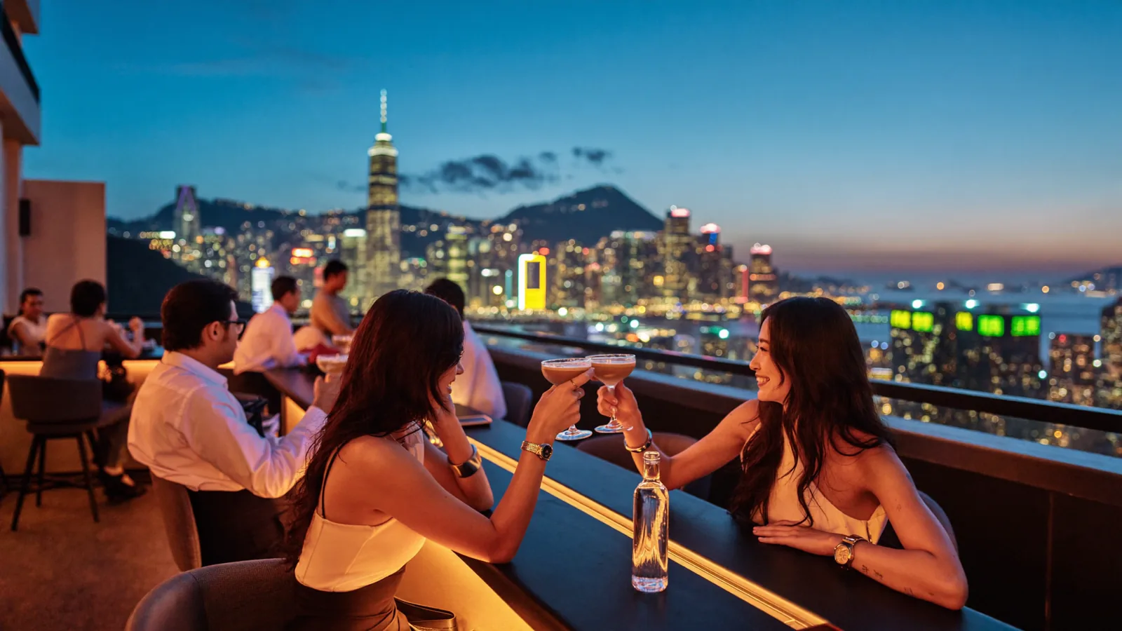A Hong Kong rooftop terrace at dusk with the city skyline beyond, illustrating YumChaNow's guide to Mega Sky, the free rooftop garden on L18 of MegaBox in Kowloon Bay