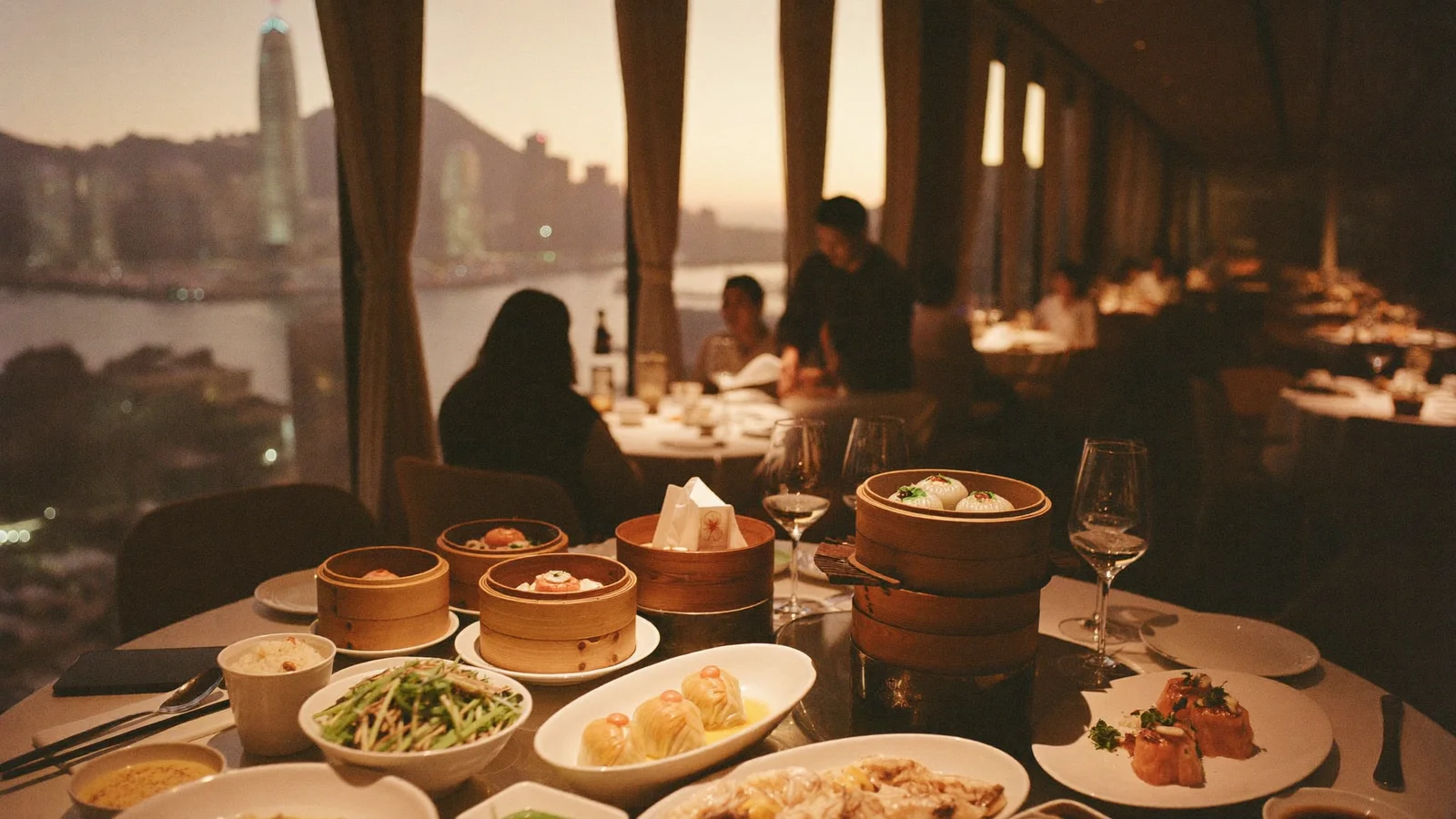 A sky-high Chinese dining room with harbour views, dim sum baskets and seafood dishes on a round table, local Hong Kong Chinese diners softly blurred in the background, illustrative image for this Tsim Sha Tsui restaurant guide, not a photo of the actual venue