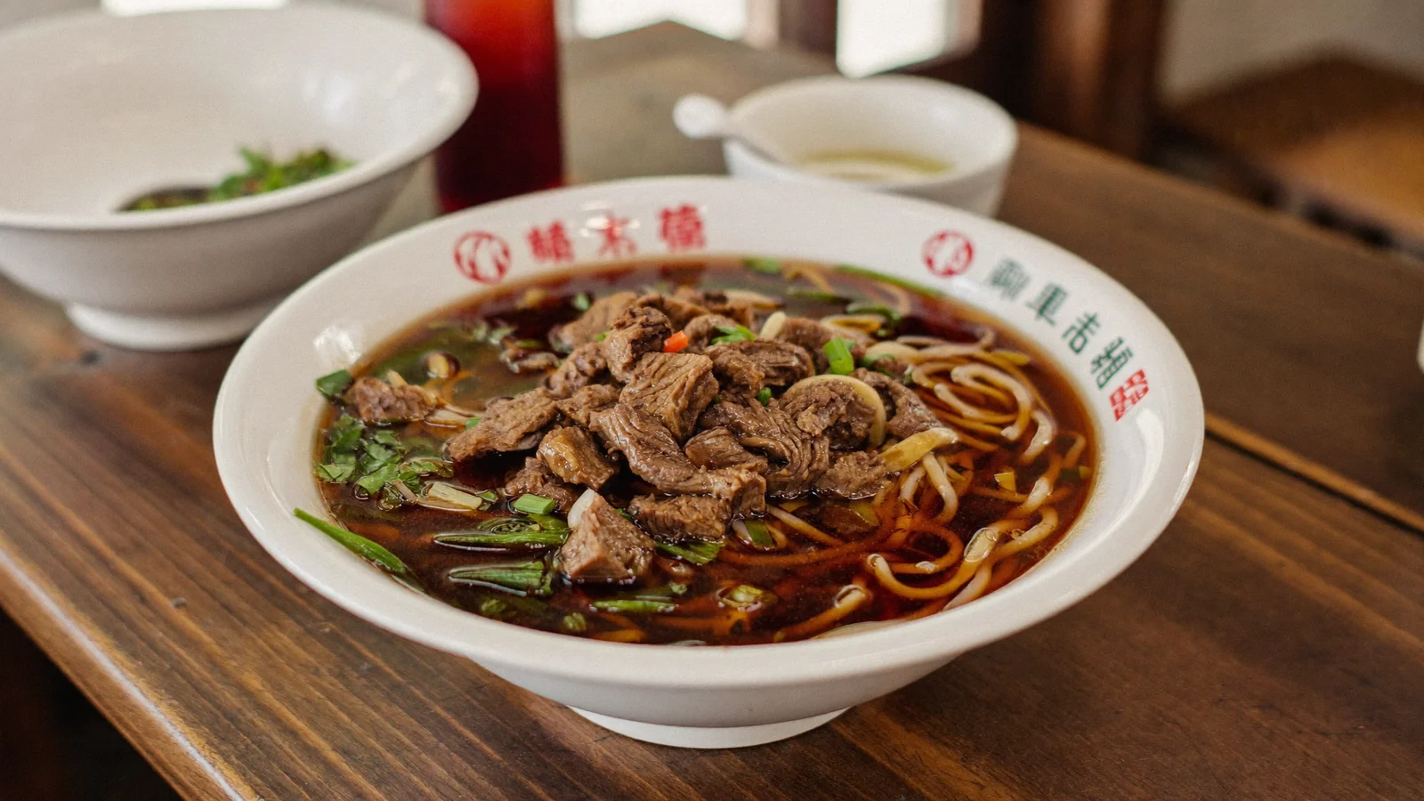 一碗熱氣騰騰嘅粵式炆牛腩湯麵，深色濃郁湯底配新鮮麵條放喺木枱上 —— 此為前廳灣仔指南嘅示意圖片，並非該店實景照片