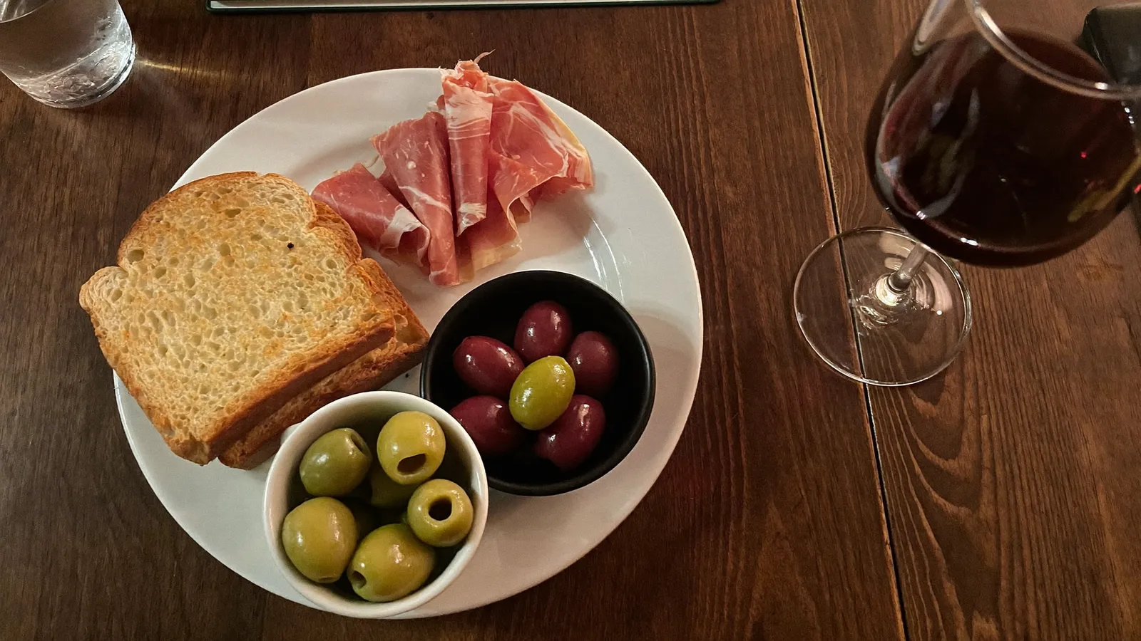 A table of Spanish tapas dishes including pan con tomate, jamon and a glass of red wine at a warmly lit Hong Kong restaurant, illustrative image for this Eat Spain Drink Spain 2026 guide, not a photo of any specific participating venue