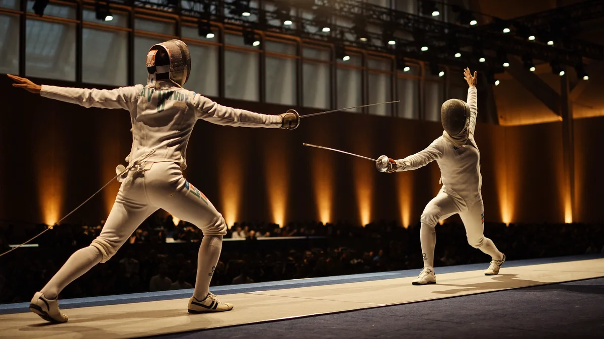 Two fencers in white kit and masks face off on the piste under arena lights, evoking the 2026 World Fencing Championships at AsiaWorld-Expo in Hong Kong