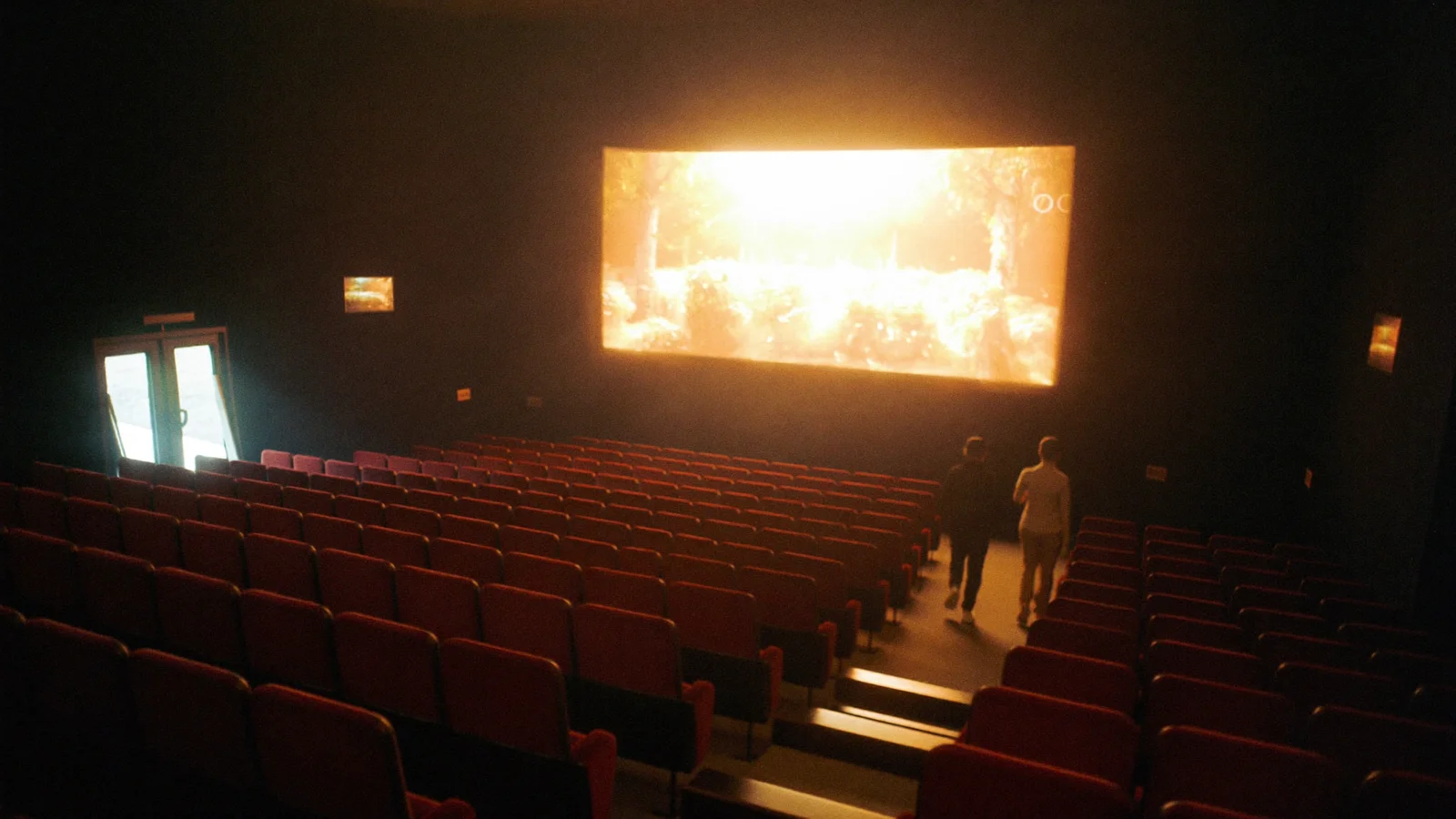 Rows of empty red cinema seats in a warmly lit arthouse auditorium with a glowing screen in the background, illustrative image for this Hong Kong Lesbian and Gay Film Festival guide, not a photo of the actual festival or venue