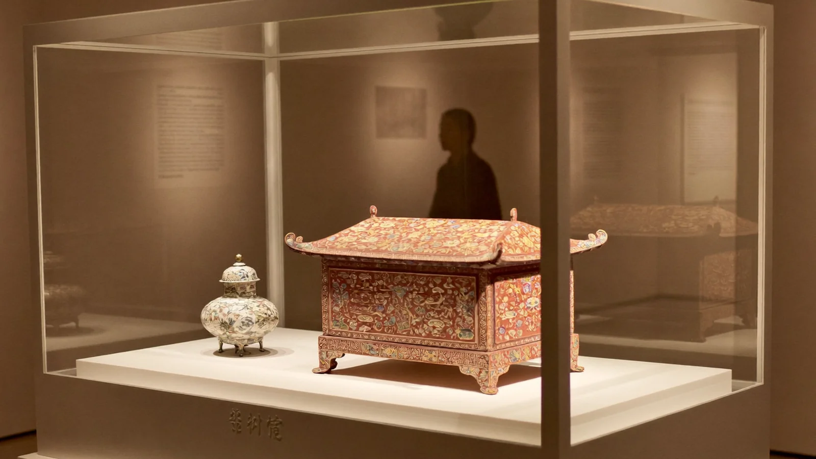 A carved Qing-dynasty imperial lacquer box and enamel vase in a warmly lit museum display case - illustrative hero for this Hong Kong Palace Museum Contemporary Design guide, not a photo of the exhibition itself