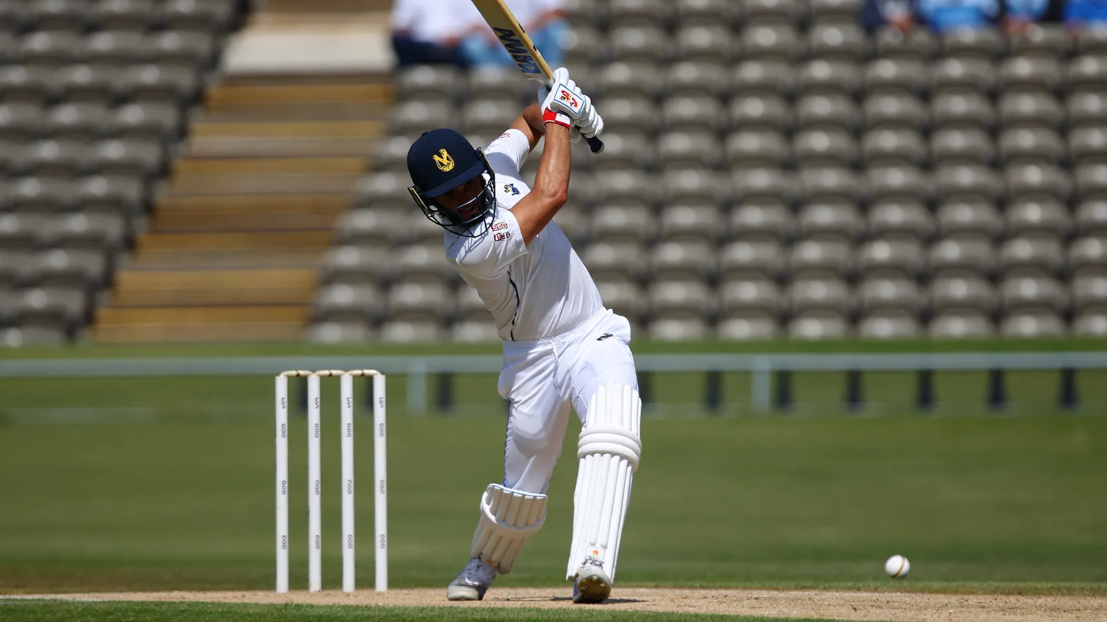 A cricket batsman mid-swing on a green pitch under bright daylight, with fielders in the background - illustrative hero for this Hong Kong Sixes cricket tournament guide