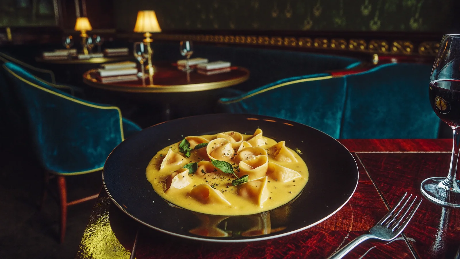 An elegant plate of handmade Italian agnolotti pasta in a rich sauce on a rosewood table with soft warm accent lighting, illustrating a guide to the new Central restaurant Il Presidente - an illustrative image, not a photo of the actual restaurant