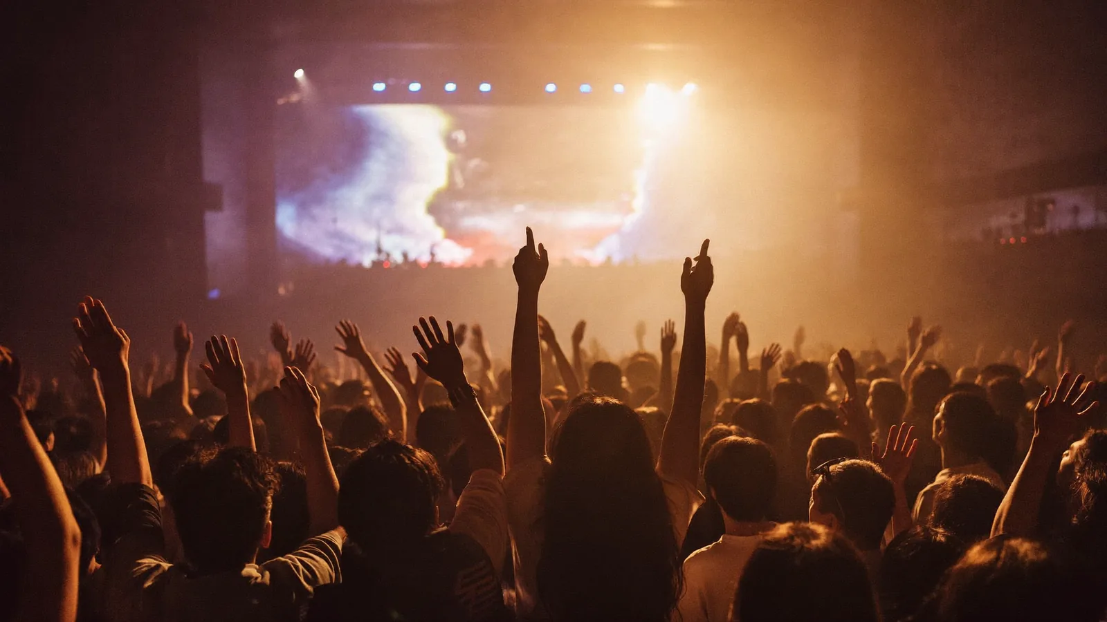 Silhouetted concert crowd with arms raised toward warm stage lights in a generic indoor hall - an illustrative image for this Joji AsiaWorld-Expo ticket guide, not a photograph of the show
