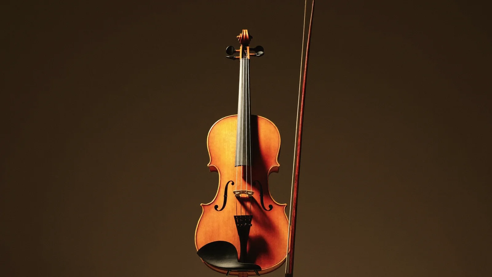 A violin and bow resting on a music stand on a dimly lit concert hall stage with a blurred orchestra of local Hong Kong Chinese musicians behind, illustrative image for this Kevin Zhu Hong Kong Sinfonietta debut guide, not a photo of the actual performance or performer