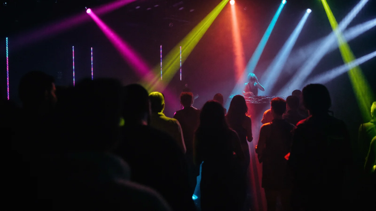 Moody nightclub interior with colourful magenta and blue stage lighting beams cutting through haze and a DJ silhouette at the decks, illustrating a guide to LABAT at Soho House Hong Kong - an illustrative image, not a photo of the actual event
