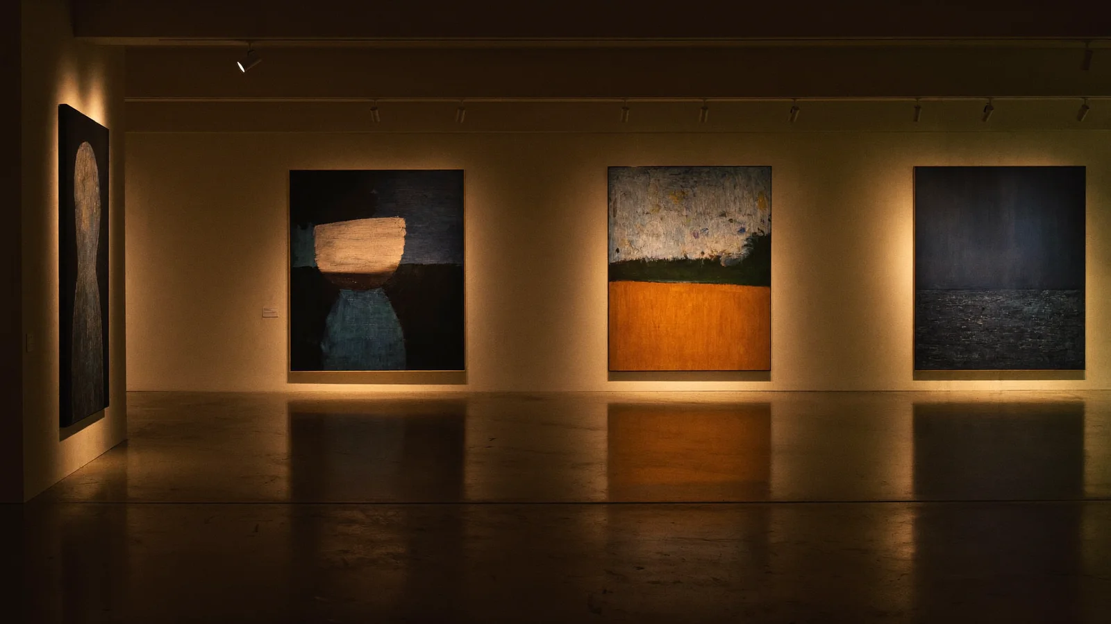 A dim, moody contemporary art gallery interior at night with abstract paintings softly lit by warm gallery spotlights, illustrating a guide to the Nocturnal group exhibition at David Zwirner Hong Kong - an illustrative image, not a photo of the actual artworks or gallery