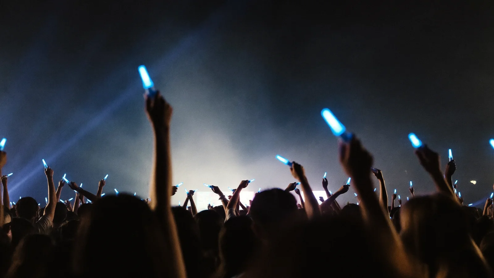 A concert crowd of local Hong Kong fans raising glowing sapphire-blue light sticks amid stage light beams - illustrative hero for this SUPER JUNIOR-83z Hong Kong guide, not a photo of the actual show
