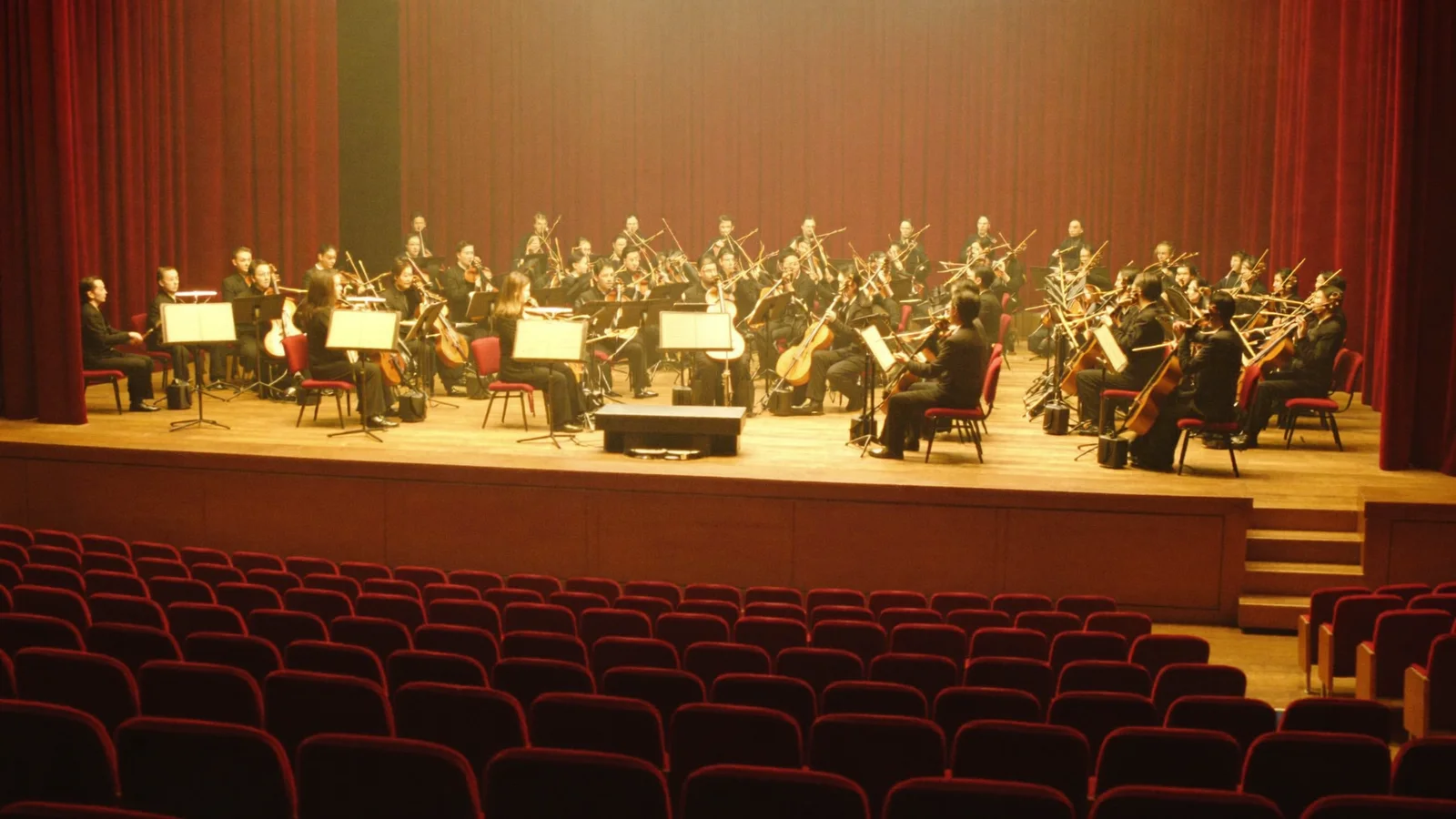 An elegant concert hall stage set for a Chinese orchestra performance, warm stage lighting on rows of traditional wind instruments including mouth organs, empty red velvet seats in the foreground, illustrative image for this HKCO Thousand Reeds One Universe concert guide, not a photo of the actual performers or venue