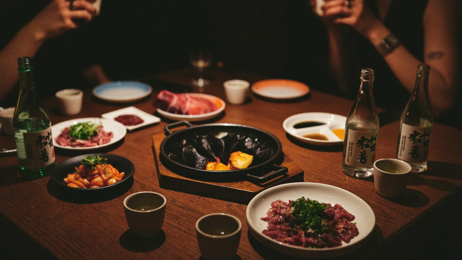 一枱韓式炭火燒肉同小份分享菜，配上米酒杯同酒樽 —— 此為中環 YuSang 搶先睇嘅示意圖片，並非餐廳實照